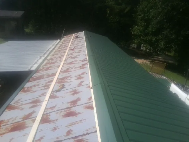Old rusted panels beside newly installed green metal roofing — Wind Damage Roof Repair by Roofing Brothers in Batesburg