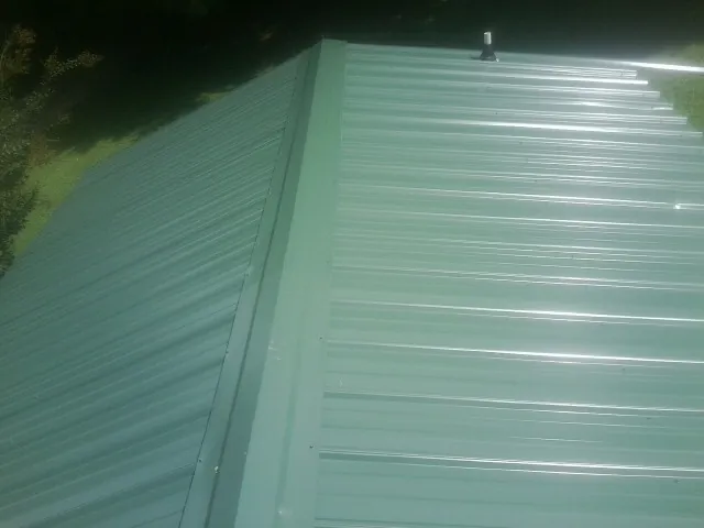 New green metal panels meeting at the ridge of a roof — Flat Roof Repair work by our crew in Batesburg