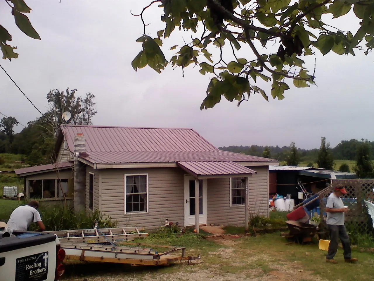 Crew finishing a mauve metal roof on a small farmhouse in Batesburg