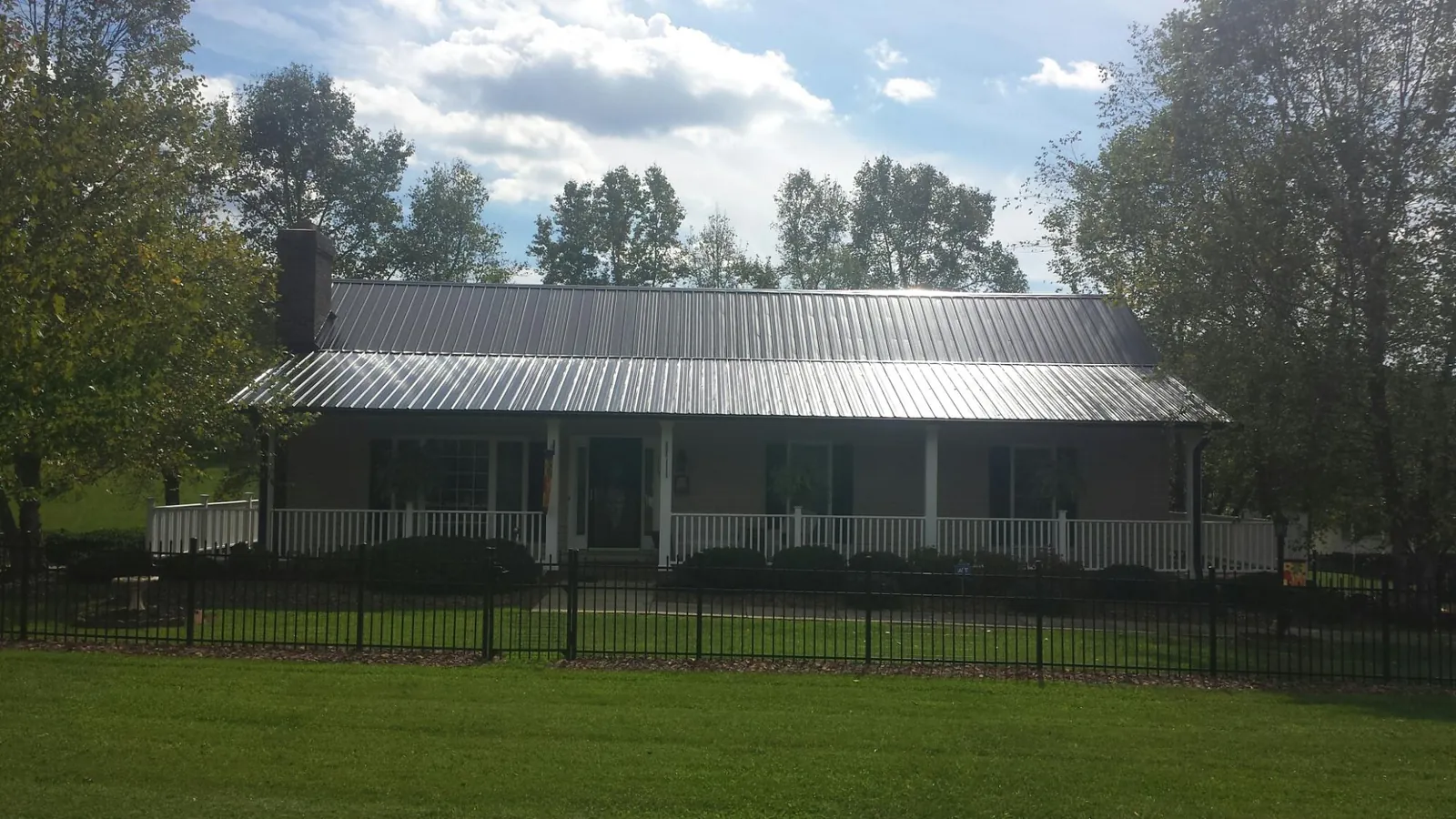 Gray metal roof on a brick ranch with a full width front porch — Gutter Guard Installation work by our crew in Batesburg