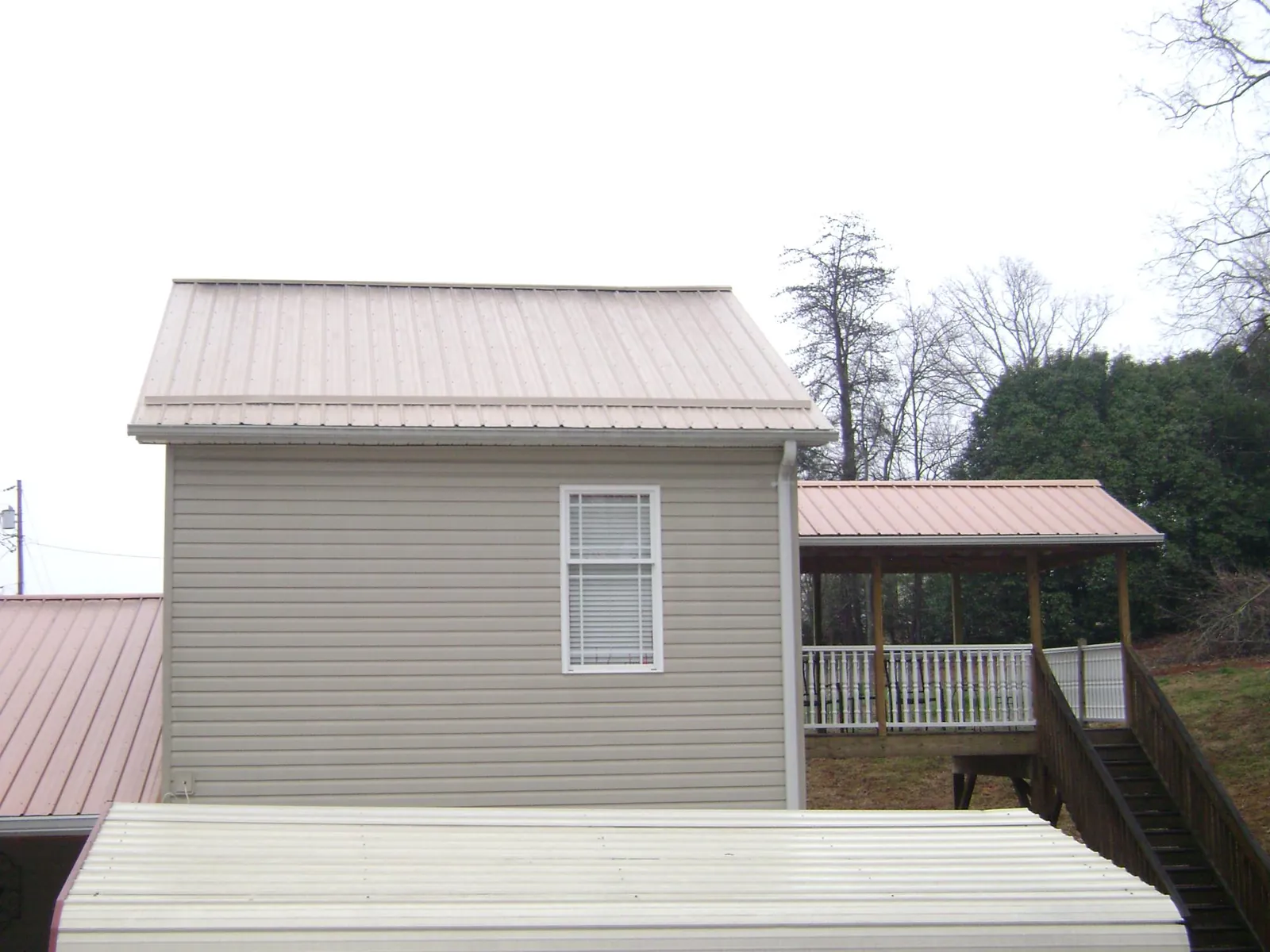 Tan metal roofs on a two story addition and attached porch, from a Roof Replacement job in Batesburg