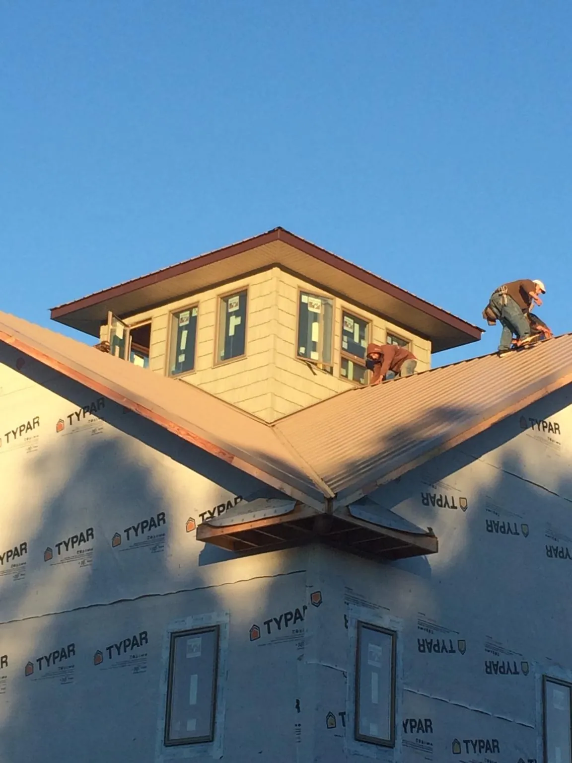 Roofers working around a rooftop cupola on a new metal roof at sunset — Roof Waterproofing in Batesburg by Roofing Brothers